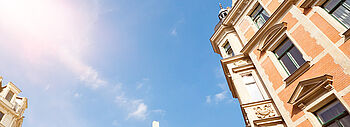 Lohnt sich Photovoltaik: Hohe Altbau-Gebäude werden im Hintergrund und ein sonniger blauer Himmel.