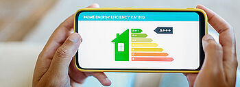 COP der Wärmepumpe: Hände halten Smartphone mit Energieeffizienz Grafik